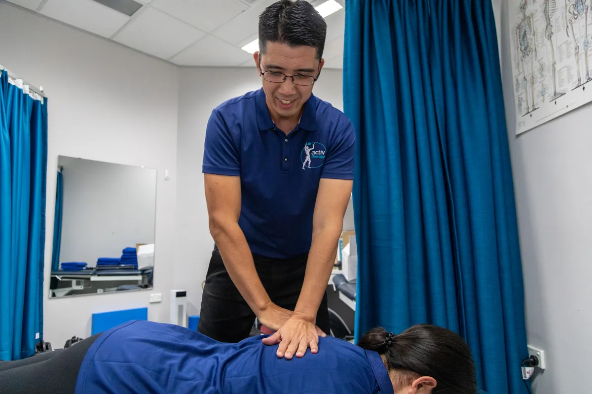 Physiotherapist mobilising a patient’s lower back on a treatment table