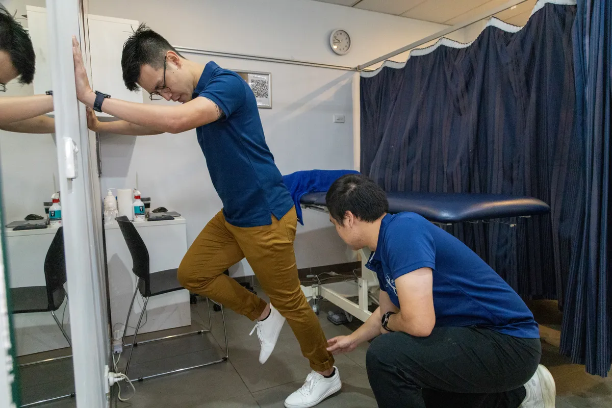 Physiotherapist correcting a patient’s position during a hip exercise