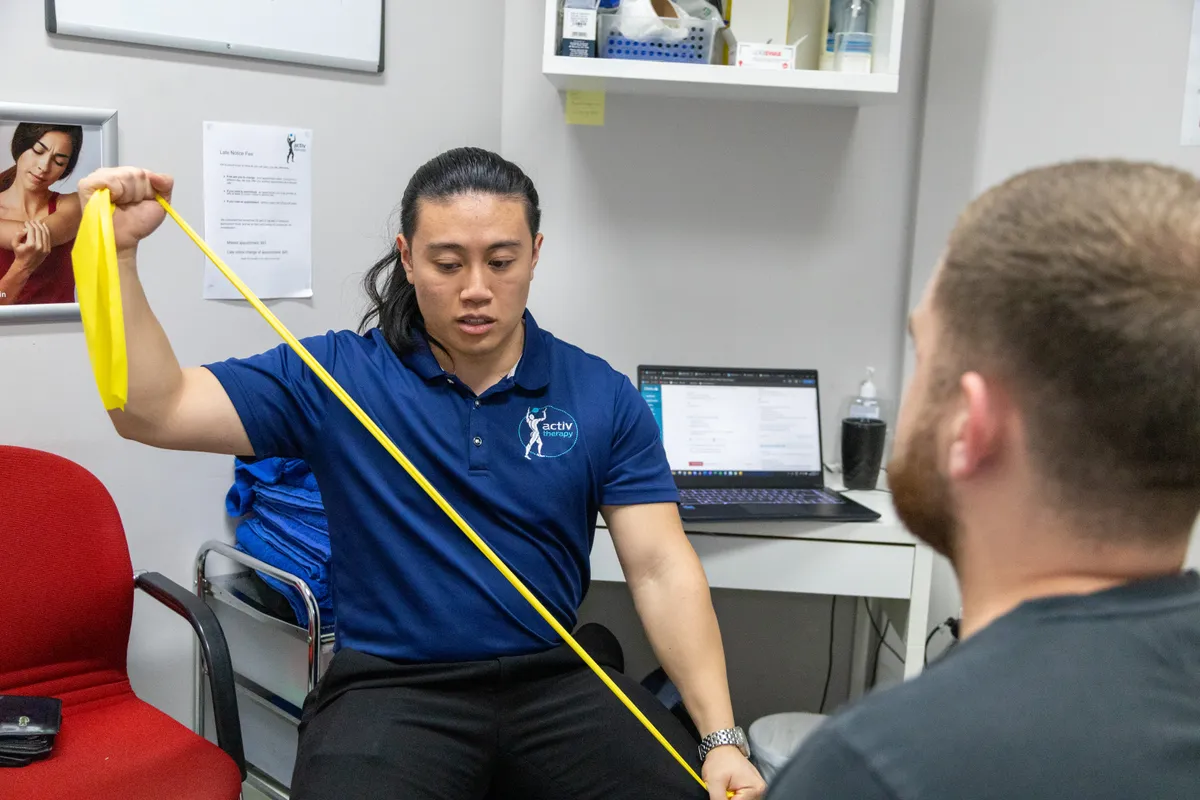 Physiotherapist demonstrating a resistance band exercise for shoulder rehabilitation