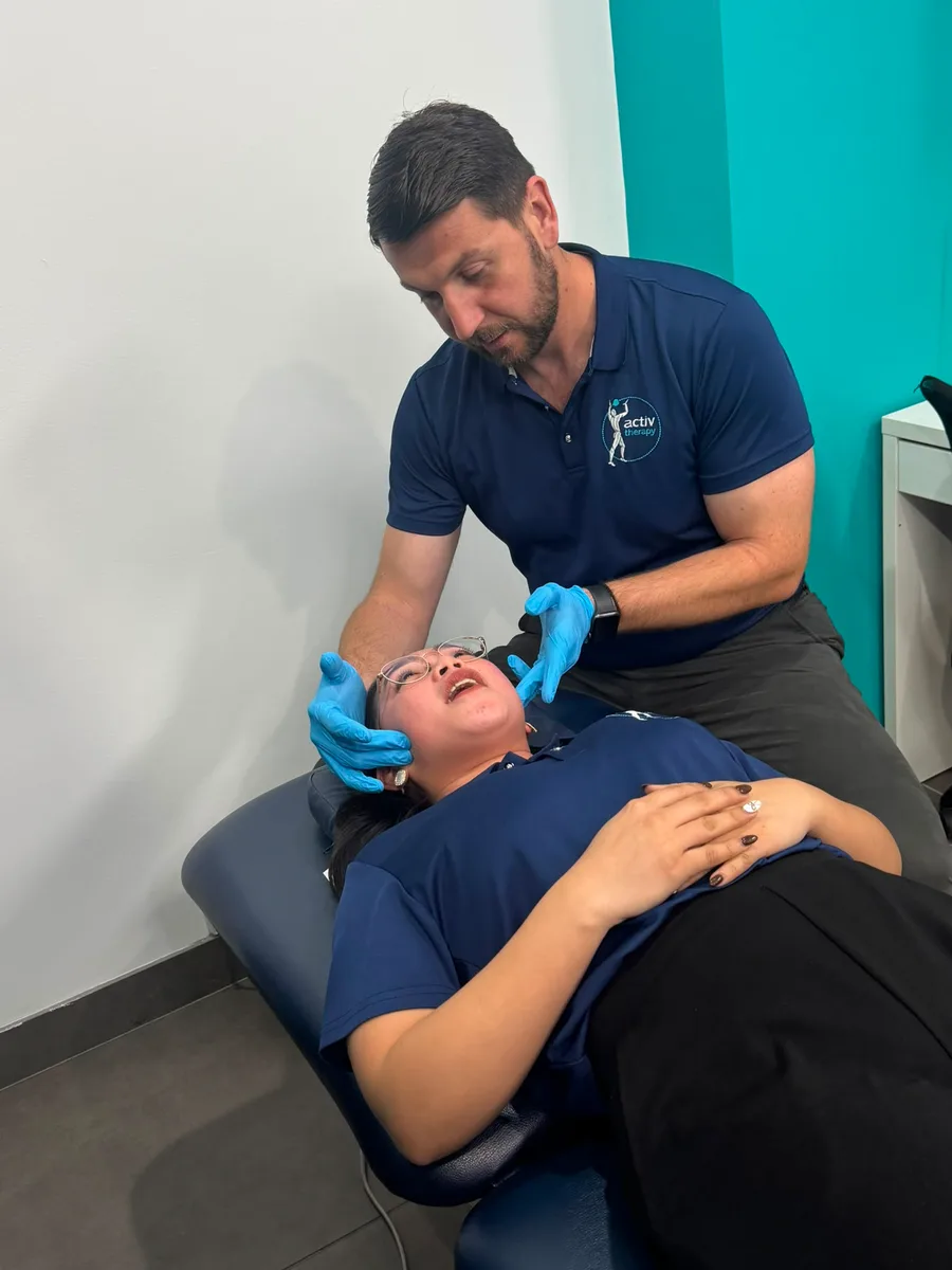Physiotherapist assessing the temporomandibular joint and jaw movement with gloved hands